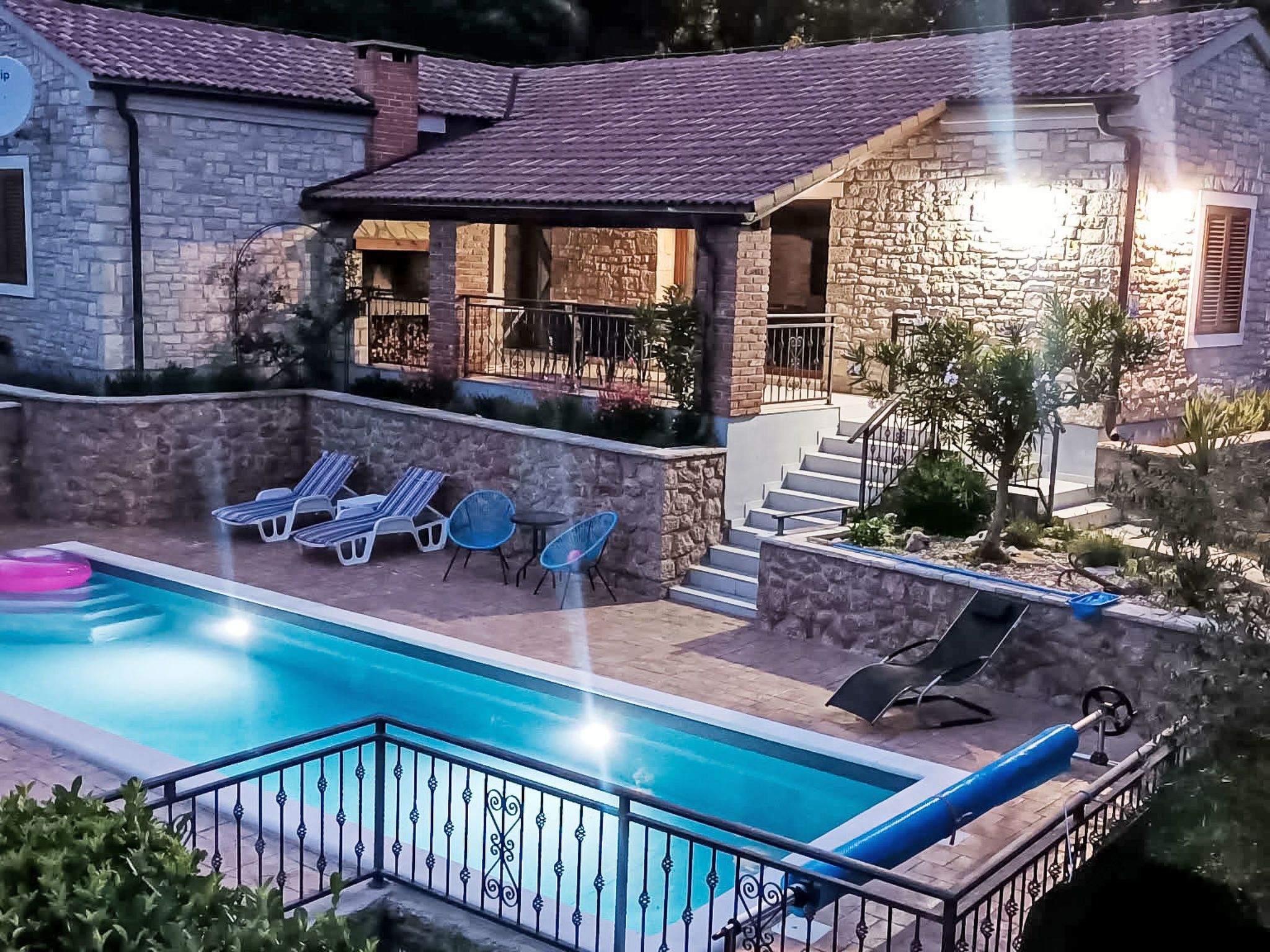 A pool area with lounge chairs and a slide, surrounded by stone buildings with a covered patio.