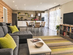 A modern living room with a sofa, coffee table, and a flat-screen TV. - Chalet Houbovy vrch by Interhome (Horni Plana)