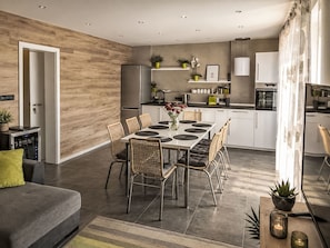 A modern kitchen with a dining area, featuring a large table, chairs, and a refrigerator. - Chalet Houbovy vrch by Interhome (Horni Plana)