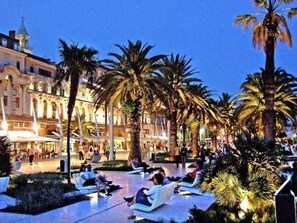 A plaza with palm trees, benches, and people sitting. - Apartment Stanić - home away from home! by Interhome (Dragovode)