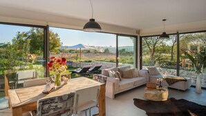 Uma sala de estar ampla com uma janela grande, uma mesa de jantar de madeira, um sofá e uma mesa de centro.