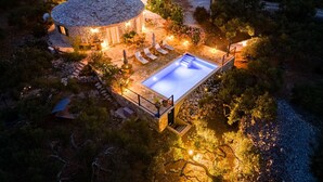 Una casa de piedra con piscina, rodeada de mobiliario de exterior y un jardín.