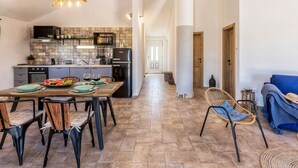 Una cocina amplia con comedor, que presenta una lámpara moderna, un respuesto de azulejos y un refrigerador negro.