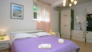 Een slaapkamer met een bed, nachtkastjes, een kledingkast en een raam met gordijnen.