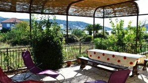 Eine Außenpatio mit überdachter Sitzgruppe, Steinböden und Blick auf die umliegende Landschaft.
