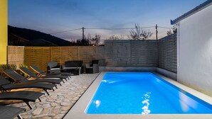 Ein Swimmingpool mit Liegestühlen und einer Steinterrasse.