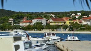 Ein Yachthafen mit vertäuten Booten, ein Strand und Häuser im Hintergrund.