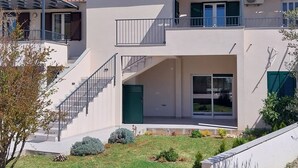 A two-story building with a flat roof, a balcony, and a staircase leading to the upper floor. - Strandappartement Ana mit Meerblick, Garten, Grillplatz by Interhome (Dragišina)