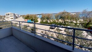 A balcony with a view of a parking area, a blue truck, and a body of water in the distance. - Strandappartement Ana mit Meerblick, Garten, Grillplatz by Interhome (Dragišina)
