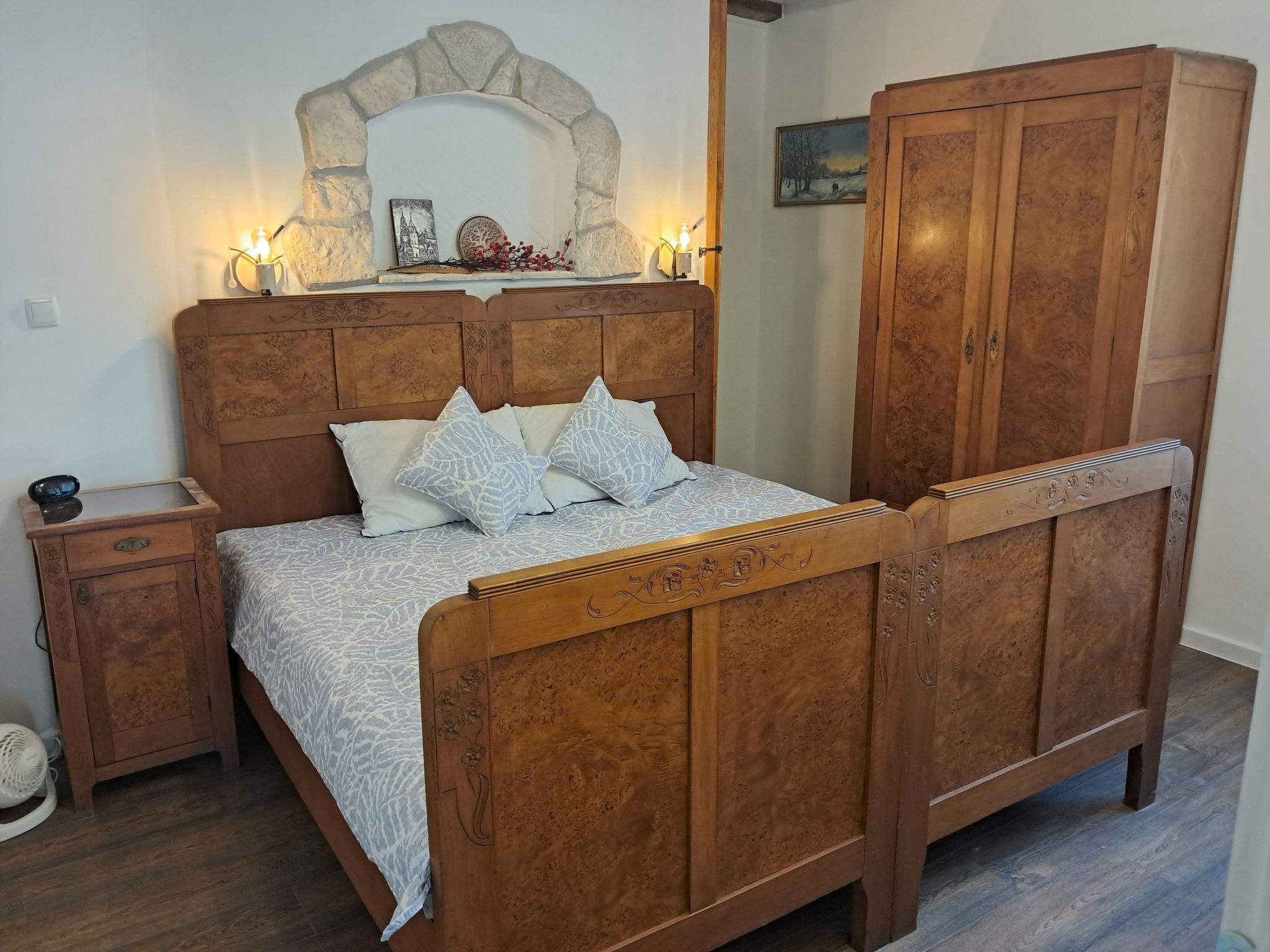 A wooden bed with a carved headboard, a nightstand, and a wardrobe.