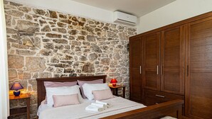 Ein Schlafzimmer mit Steinwand, hölzernem Bettgestell und einem großen Kleiderschrank.