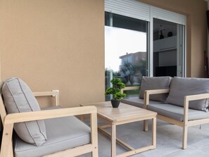 Ein Balkon mit zwei grauen Sofas, einem kleinen Holztisch und einem Blumentopf.