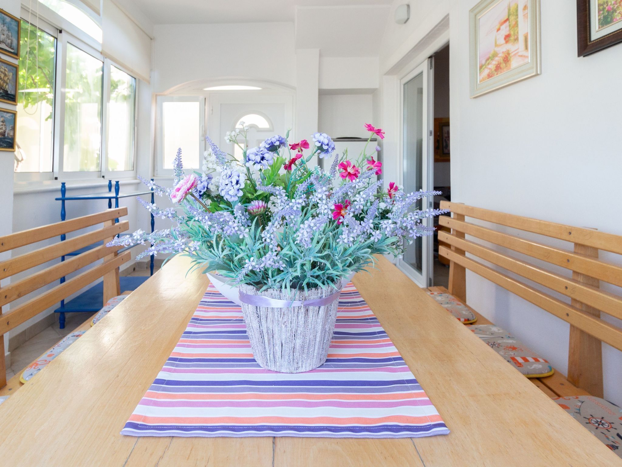 Ein Essbereich mit einem Holztisch, einem gestreiften Tischläufer und einer üppigen floralen Dekoration.