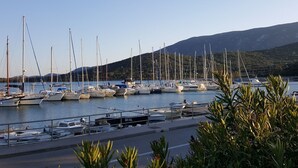 Una marina amb diverses embarcacions amarrades, envoltada de vegetació i amb turons al fons.