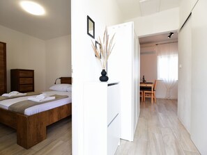 A bedroom with a wooden bed, a white wardrobe, and a small table with a vase of dried plants. - Wohnung mit Garage by Interhome (Krneza)