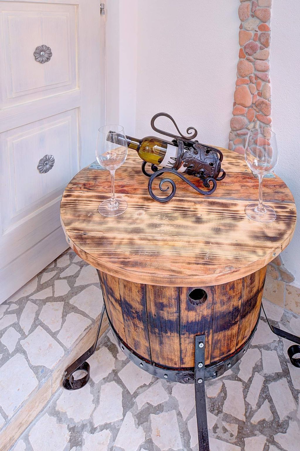 Un tavolo di legno tondeggiante con una bottiglia di vino e due bicchieri.