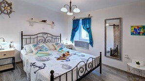 Ein Schlafzimmer mit Bett, Nachttischen, einem Spiegel, einem Fenster mit Vorhängen und einem Deckenventilator.