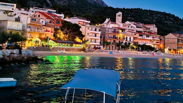 A coastal town with buildings along the waterfront, a clear sky, and a boat docked in the foreground. - Villa Margitta mit Pool, Tennisplatz und Meerblick by Interhome (Drašnice)