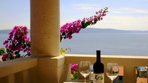 A balcony with a table, a bottle of wine, and two wine glasses. - Villa Margitta mit Pool, Tennisplatz und Meerblick by Interhome (Drašnice)