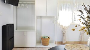 A modern room with a flat-screen TV mounted on the wall, a white wardrobe, a wicker basket on the floor, and a window with sheer curtains. - Kleines Steinhaus in einem ruhigen Ort auf der Insel Solta by Interhome (Gornje Selo)