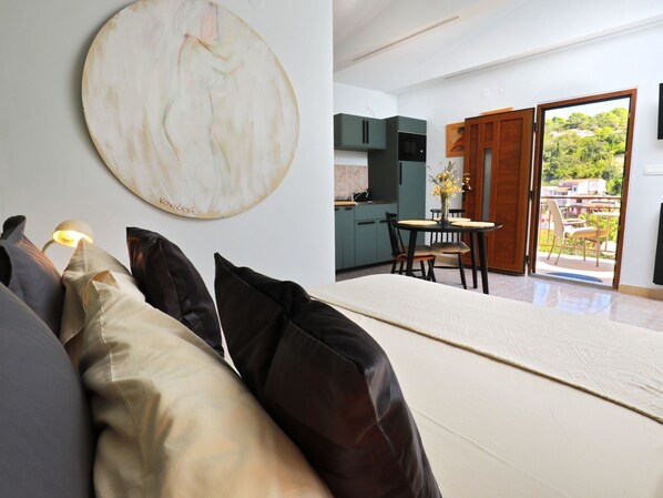 A modern living room with a sofa, a dining table with chairs, a kitchen area, and a sliding glass door leading to an outdoor patio. - Kleines Steinhaus in einem ruhigen Ort auf der Insel Solta by Interhome (Gornje Selo)