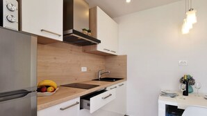 Una cocina moderna con un refrigerador de acero inoxidable, una encimera de madera, un lavamanos negro y una zona de comedor con mesa y sillas.