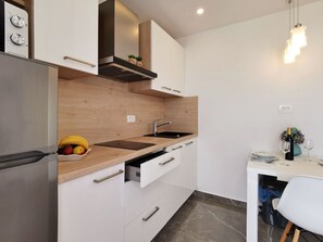Eine moderne Küche mit einem Edelstahlkühlschrank, einer Holzausziehtischplatte, einer schwarzen Spüle und einem Essbereich mit Tisch und Stühlen.