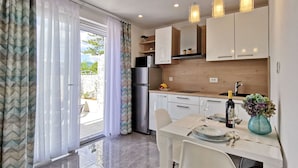 Una cocina moderna con armarios blancos, un refrigerador de acero inoxidable y un comedor con una mesa lista para dos personas.