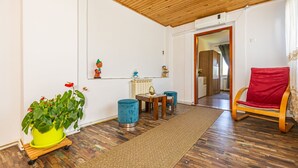 Una sala de estar acogedora con techo de madera, una zona de comedor con una mesa y sillas pequeñas, y un sillón rojo.