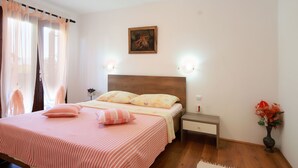 Un dormitorio con una cama, mesitas de noche, un cuadro y un florero con flores.