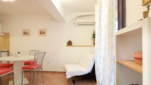 Una habitación acogedora con una mesa de comedor, sillas, una cama y una estantería con adornos.