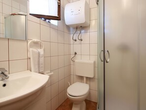 A bathroom with a white sink, toilet, and a glass shower enclosure. - Svoboda 4 by Interhome (Krk/Šilo)