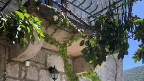 An outdoor seating area with a stone table and wicker chairs, surrounded by a stone wall with ivy. - "Kastil" mit privatem Pool by Interhome (Zrnovo)