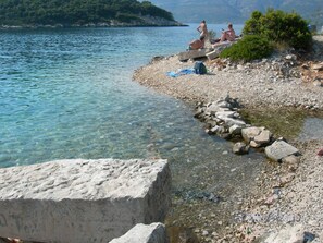 Eine felsige Küstenlinie mit klarem Wasser, einige entspannte Personen und ein Stempel mit dem Datum 22.07.2006.