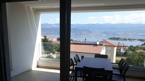 A balcony with a table and chairs, overlooking a lake and mountains. - für 5 Personen ca. 68 m² in Šilo, Adriaküste Kroatien (Kroatische Inseln) by Interhome (Krk/Šilo)