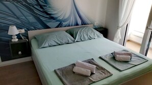 A bedroom with a large bed, two pillows, a nightstand with a lamp, and a wall mural. - für 5 Personen ca. 68 m² in Šilo, Adriaküste Kroatien (Kroatische Inseln) by Interhome (Krk/Šilo)