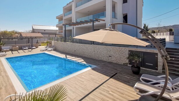 A modern building with a swimming pool, sun loungers, and a pergola. - für 5 Personen ca. 68 m² in Šilo, Adriaküste Kroatien (Kroatische Inseln) by Interhome (Krk/Šilo)