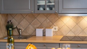A kitchen with grey cabinets, a tiled backsplash, a wooden countertop, a sink, and a basket of bread. - Gemütliche Ferienwohnung Tina 4 by Interhome (Krk/Šilo)