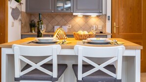 A kitchen with a wooden island, two white chairs, and a hanging light fixture. - Gemütliche Ferienwohnung Tina 4 by Interhome (Krk/Šilo)