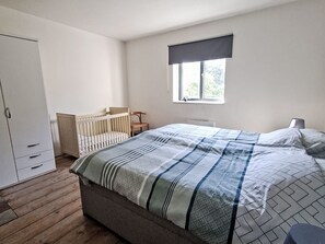 Een slaapkamer met een bed, ledikant, kledingkast en raam.