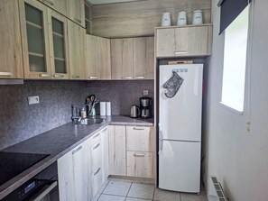 A kitchen with wooden cabinets, a refrigerator, a coffee maker, and a sink.