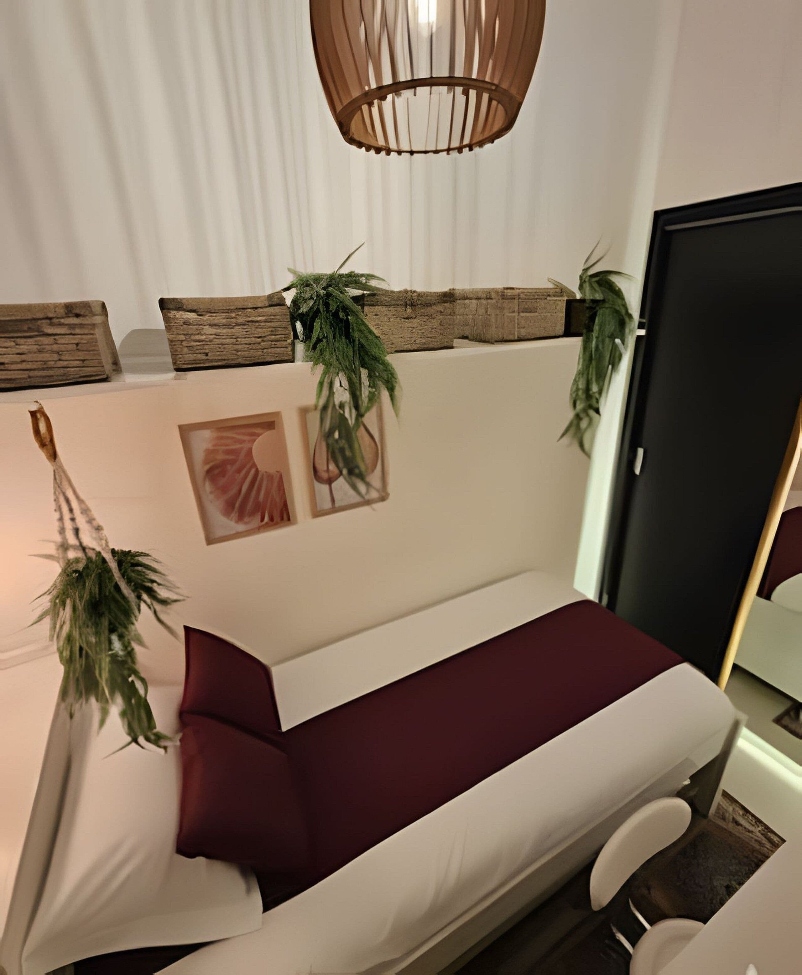 Ett modernt, minimalistiskt rum med en vit soffa, röda kuddar och dekorativa växter.