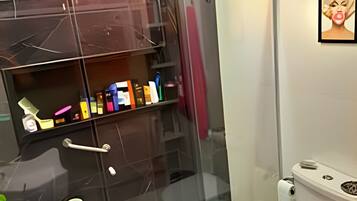 A bathroom with a glass-enclosed shower, a white toilet, and a sink.