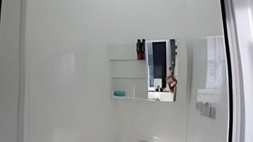 A small, modern bathroom with a toilet, a shower, and a mirror.