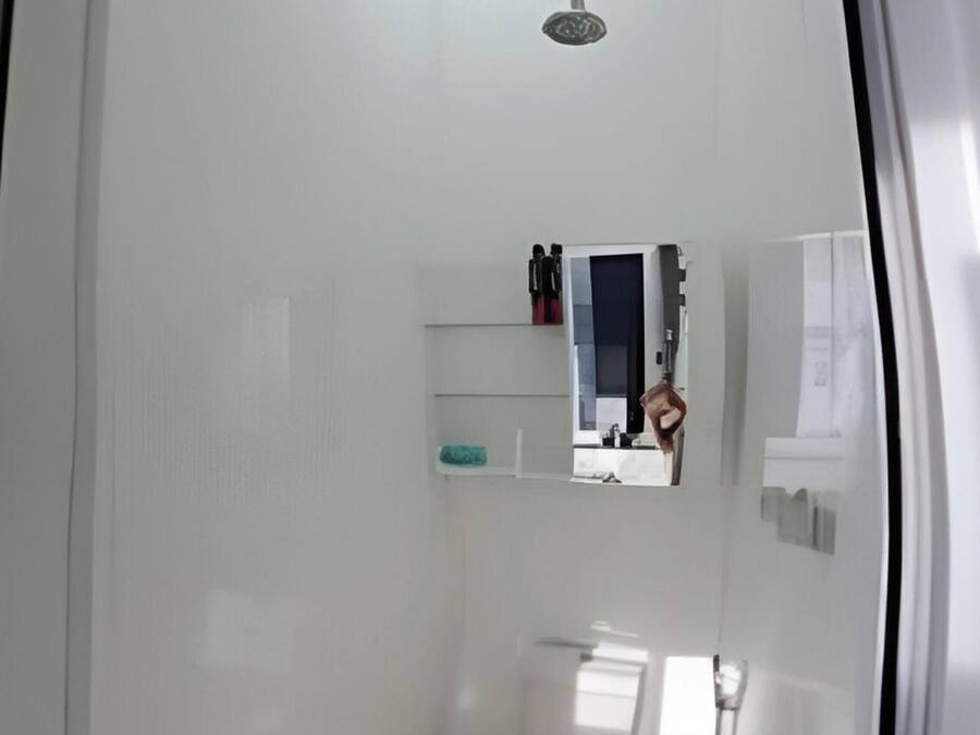 A small, modern bathroom with a toilet, a shower, and a mirror.