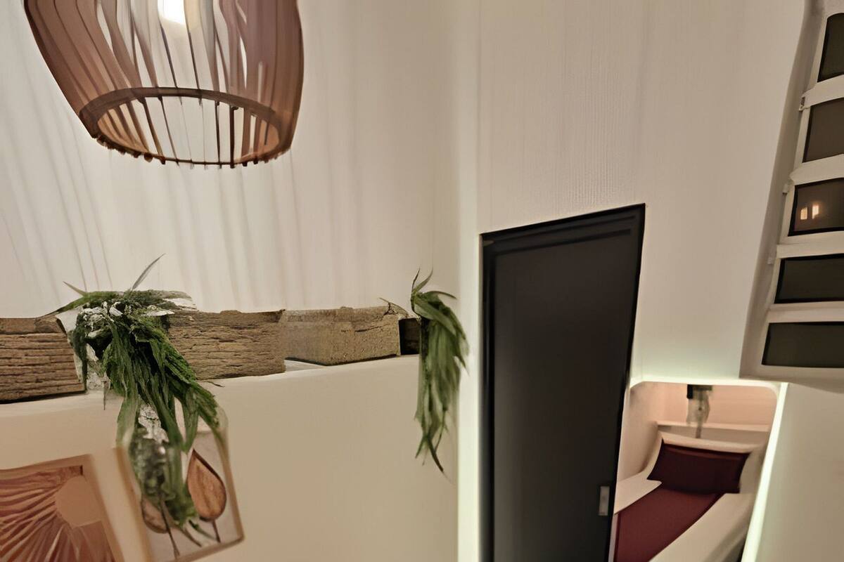 A modern bedroom with a white bed, dark red bedding, a wooden headboard, and a hanging plant.