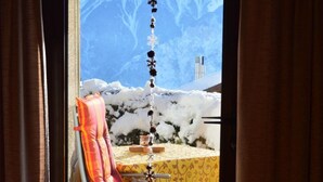 Ein Stuhl mit Kissen und ein Tisch mit gemustertem Tischläufer, beide draußen in verschneiter Umgebung.
