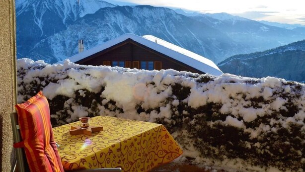 Ein gemütliches Zimmer mit Tisch für zwei Personen, einem Stuhl und Blick auf schneebedeckte Berge.