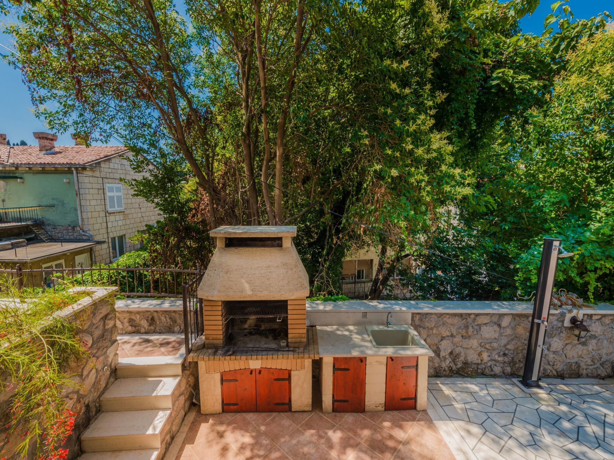 An outdoor kitchen with a stone chimney, a sink, and a small step leading up to it.