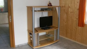 A corner room with a wooden cabinet containing a television and a small statue. - Ferien im grünen rechts by Interhome (Haldi b. Schattdorf)
